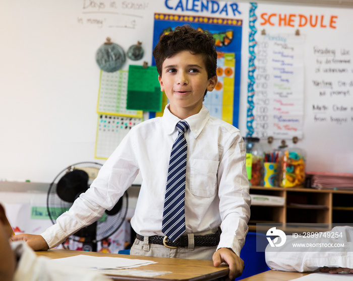 Portrait of schoolboy (10-11) standing at desk in classroom