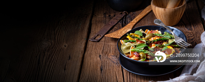 Pasta salad with green asparagus, olives and parma ham