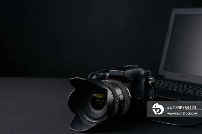 Closeup of professional  photography camera,modern laptop, home illustration & equipments on creativ