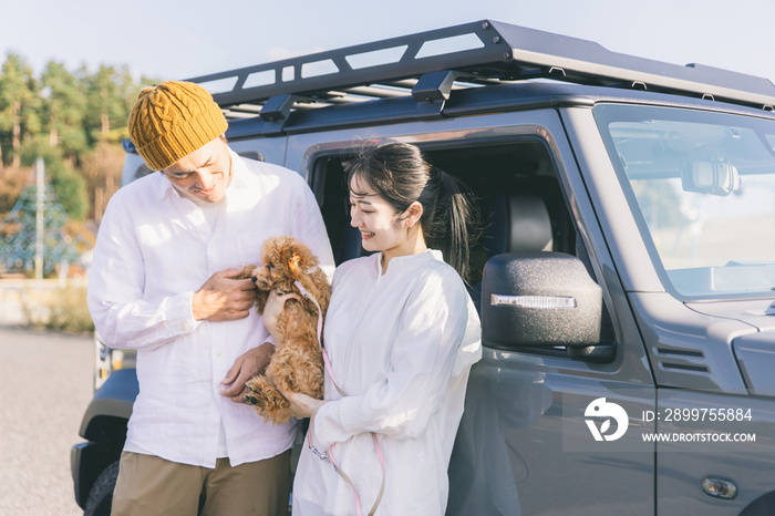 車でお出かけする犬と男女（車の前）