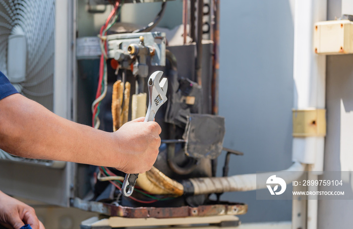 Selective focus of technician man hands holding a wrench over blurred modern air conditioning, Maint