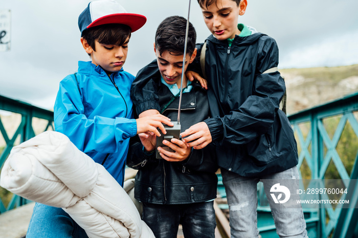 Young children using a walkie-talkie standing on train tracks