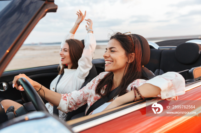 Pretty happy smiling cheery young pretty women friends driving the car.