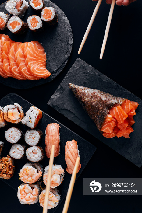 table black various sushi with hand on hashi and temaki