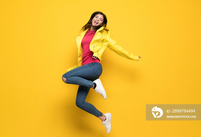 Teenager girl jumping over isolated yellow wall