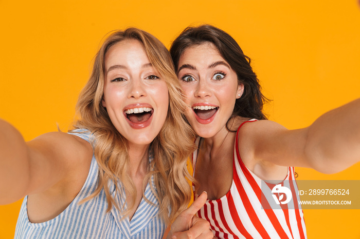 Portrait closeup of two delighted blonde and brunette women 20s in summer wear smiling while looking