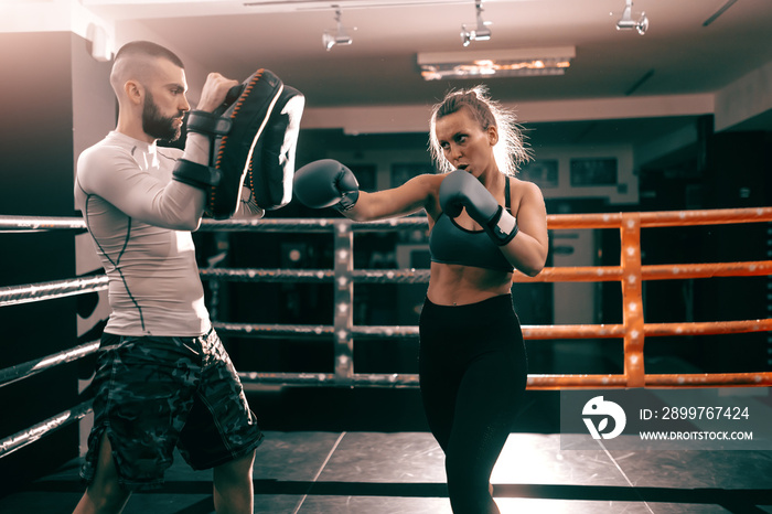 Strong muscular boxer Caucasian woman punching and having training in ring.