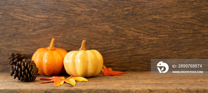 close up group of orange pumpkins ,pinecone and maple leaves lay on brown retro wood tabletop backgr