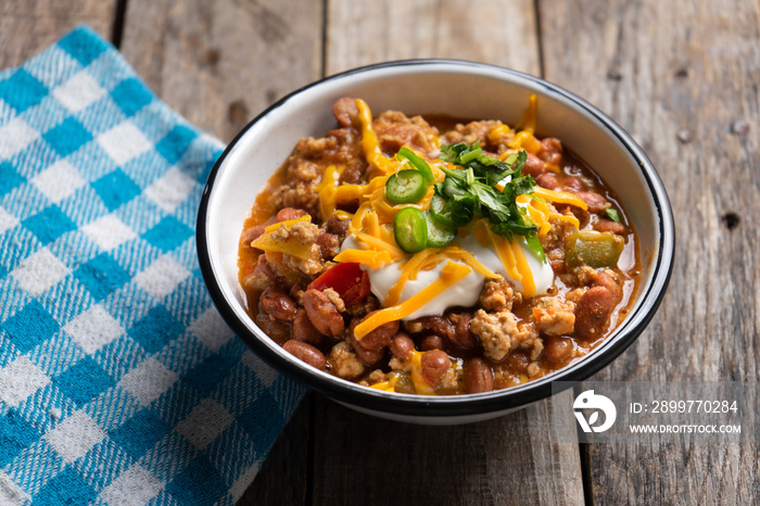 Texmex dish called  Chili con carne  with cheese and sour cream on wooden background