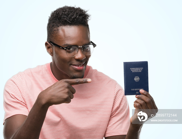Young african american man holding german passport very happy pointing with hand and finger