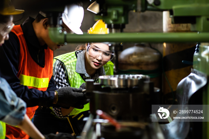 Asian Factory worker training to colleague on production line in Heavy Industry Manufacturing Facili