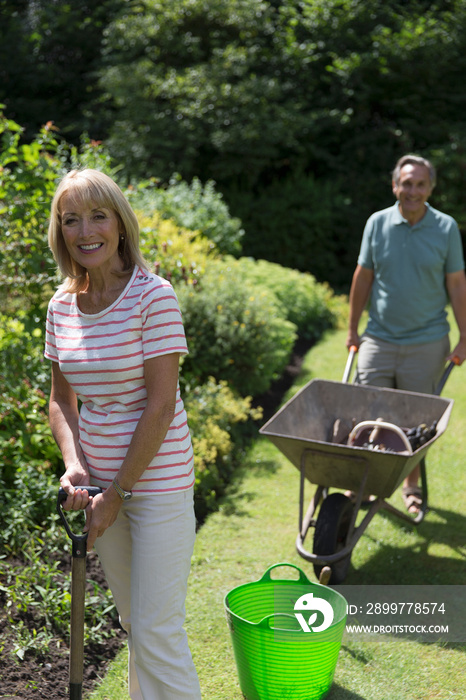 Portrait happy senior couple gardening in sunny backyard