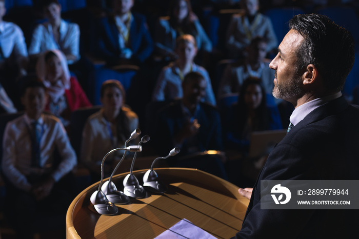 Businessman standing and giving presentation in the auditorium