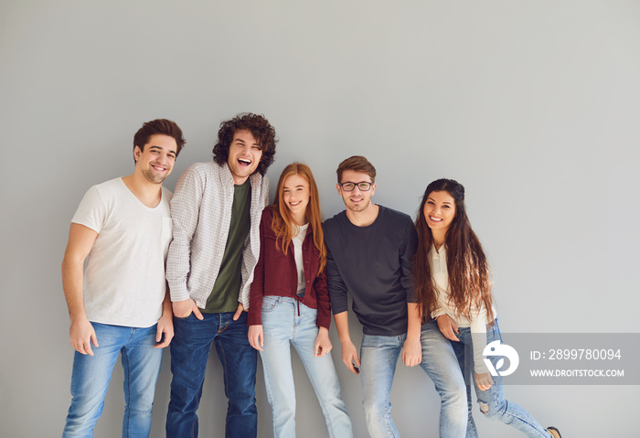 Group of young people in casual clothes smiling while gray background.