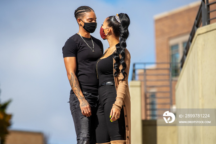 African American lesbian couple wearing black clothes and face masks to protect from Covid-19 Corona