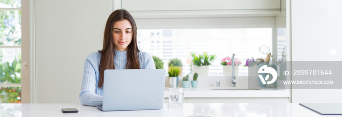 Wide angle picture of beautiful young woman working or studying using laptop with a confident expres