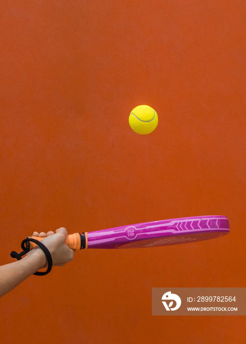 手持球拍在橙色背景下击球。运动