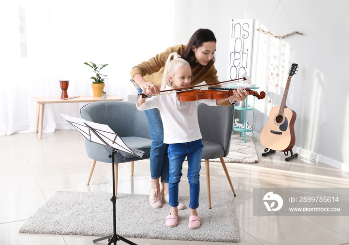 Private music teacher giving violin lessons to little girl at home