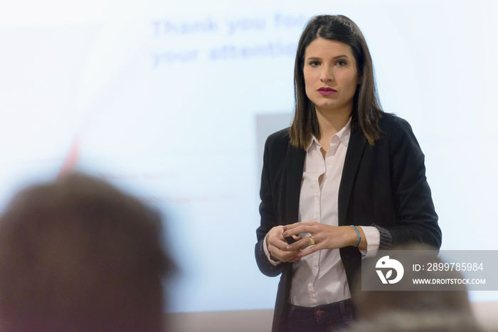 Pretty young businesswoman, teacher or mentor coach speaking to young students in audience at traini