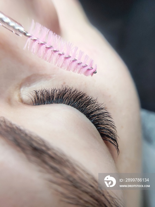 close up of lips hairing lash extensions with pink brush