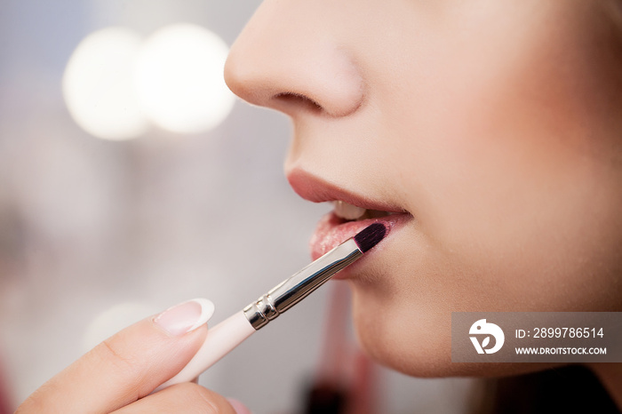 makeup artist applying lipstick on model lips with brush