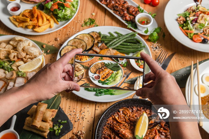 A man takes a photo of food on his smartphone at a Filipino restaurant. He shares your lifestyle on 