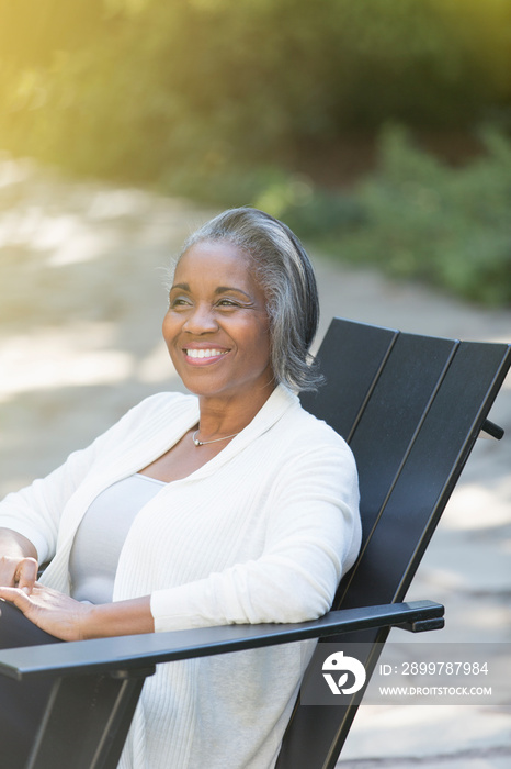 Happy senior woman relaxing in adirondack chair on patio