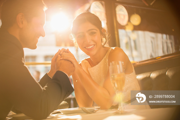 Happy couple holding hands and drinking champagne in restaurant