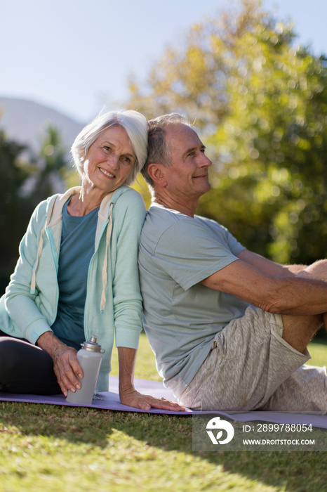 Portrait happy senior couple resting on yoga mat in grass