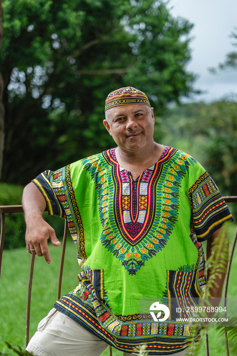 Retrato de un hombre latino muy sonriente en el exterior con una camisa muy colorida caribeña mirand