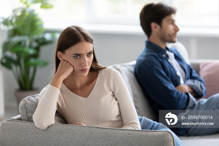 Unhappy sad european millennial husband and wife ignore each other sitting on sofa in living room