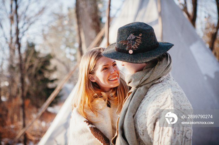 冬天，一对浪漫的情侣站在森林里的帐篷旁看着对方