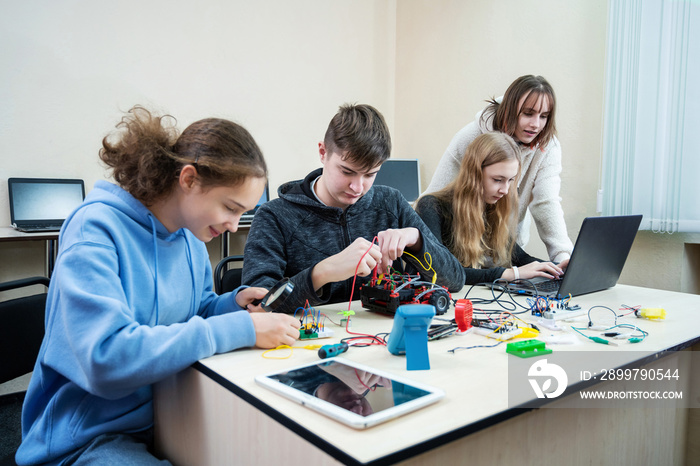 Diverse teenager pupils build robot vehicle learning at table at STEM engineering science education 