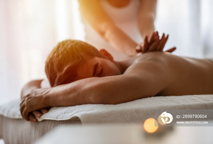 Masseur doing back massage on man body in the spa salon. Beauty treatment concept. Girl in a T-shirt