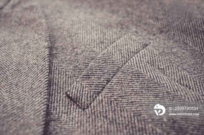 Closeup of light grey tweed woolen coat or jacket with a pocket fragment.