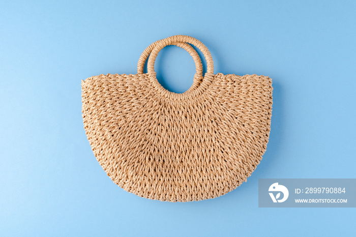 Summer straw bag on blue background. Top view