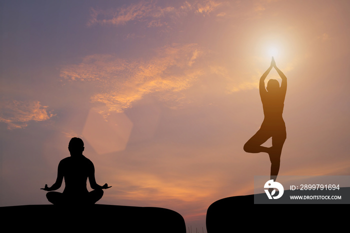 The silhouette of a woman practicing yoga on a rock during a beautiful sunset