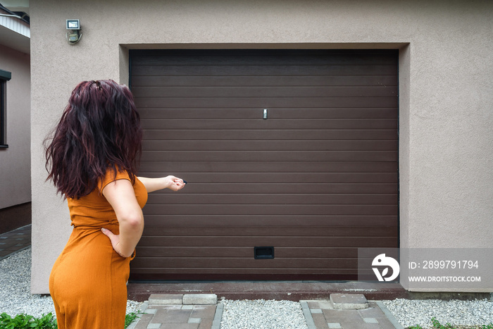 Garage door PVC. Girl or young woman holds remote controller for closing and opening garage door