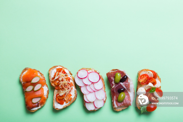 Set of colorful sandwiches prepared with different ingredients such as fish, vegetables and meat. Gr