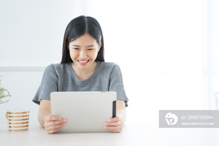 Young Asian woman using tablet at home and having breakfast in the morning .She reading on tablet.