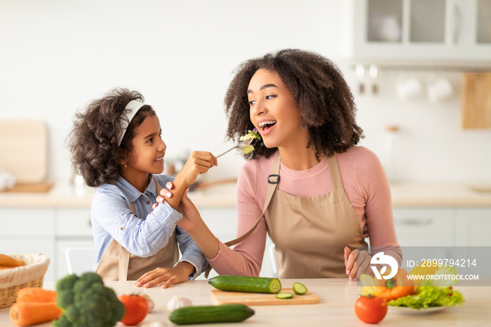 Afro Girl Feeding Young Woman With Vegetables