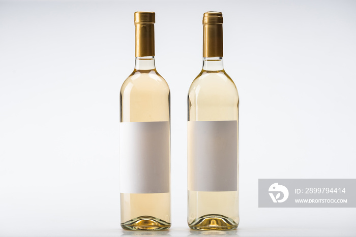 two bottles of white wine with blank labels on white background