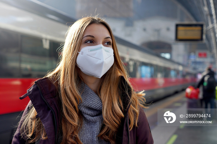 Portrait of girl wearing KN95 FFP2 medical face mask with moving train on background on train statio