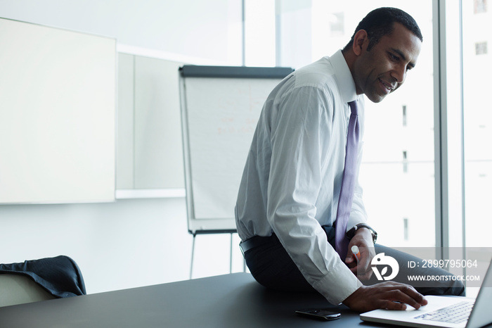 Corporate businessman using laptop in conference room