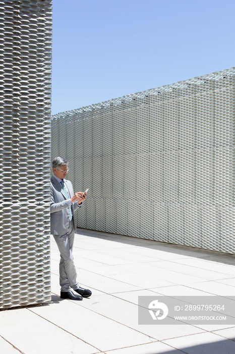 Businessman using smart phone on sunny modern rooftop