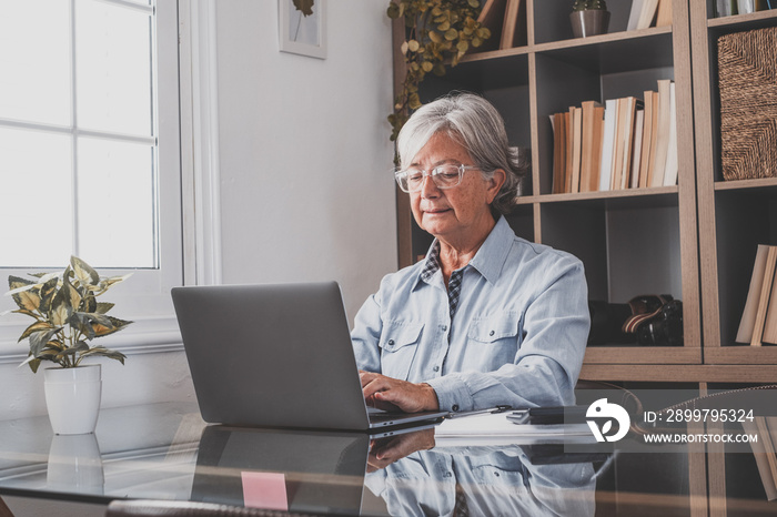 Happy old caucasian businesswoman smiling working online watching webinar podcast on laptop and lear