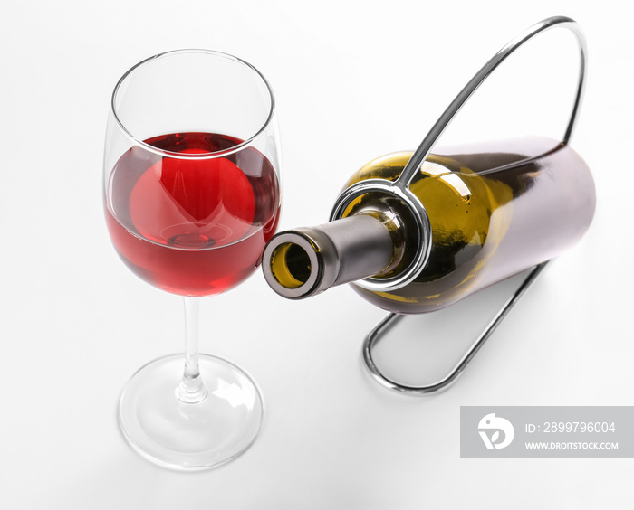 Holder with bottle and glass of wine on white background