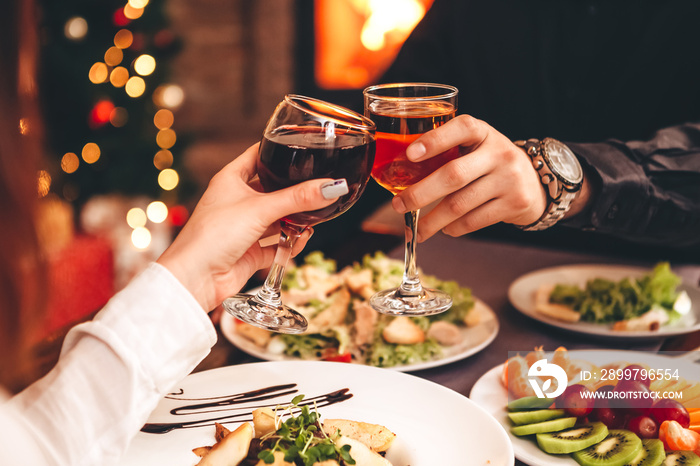 Man and woman drink red and white wine.  Сlose-up of hands with glasses. They celebrate the new year