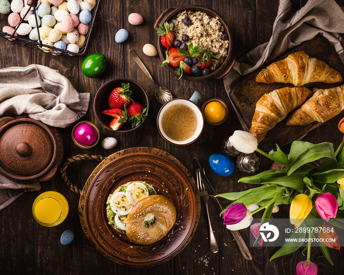 质朴的复活节早餐平躺蛋百吉饼、郁金香、羊角面包、鸡蛋、浆果燕麦片等