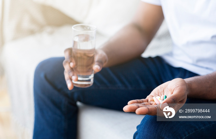 African american man holding glass of water and pills